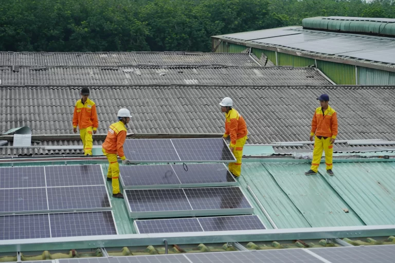 Instalación de paneles solares en un techo industrial por técnicos especializados.